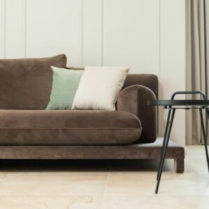 Interior of bright modern flat with couch with pillows near round table and curtains on windows